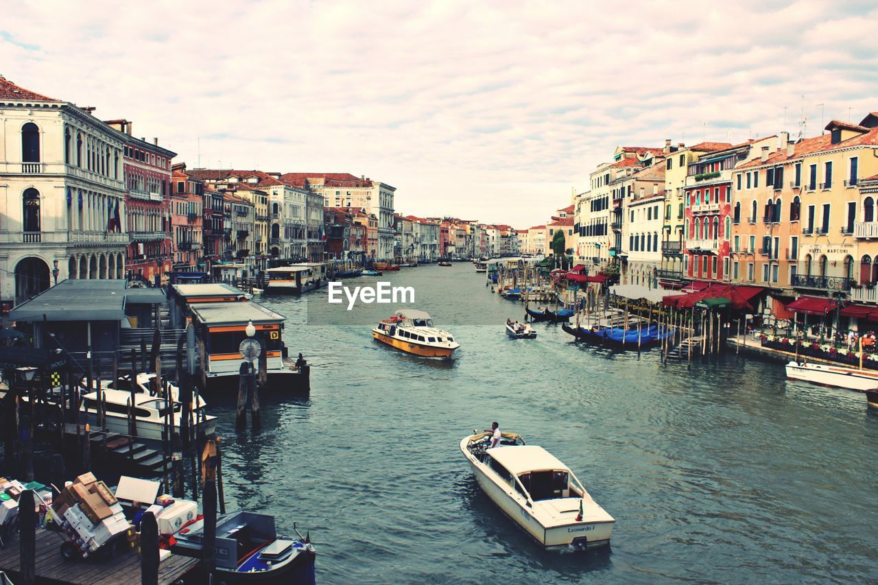 BOATS MOORED IN CANAL AMIDST BUILDINGS IN CITY