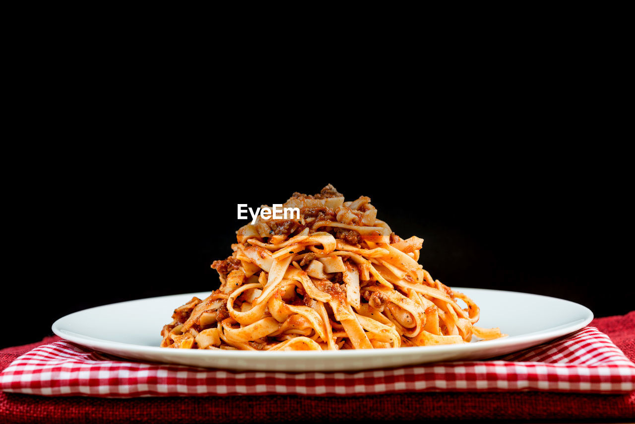 Close-up of pasta in plate against black background