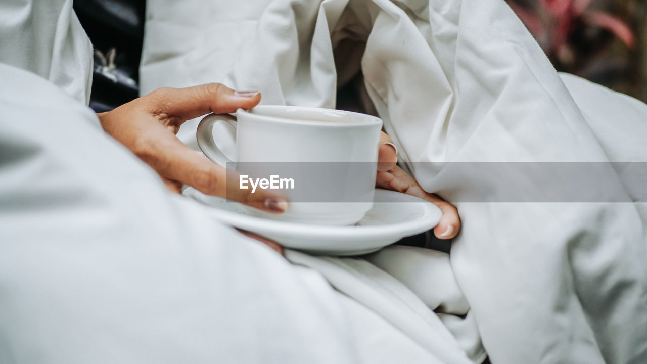 Midsection of man holding coffee cup