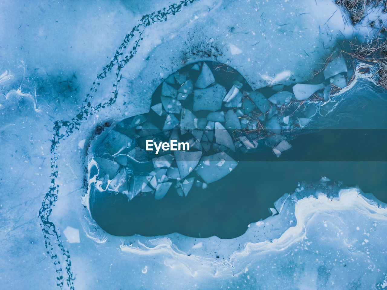 Panoramic aerial view of a frozen lake with animal tracks and cracked ice. 