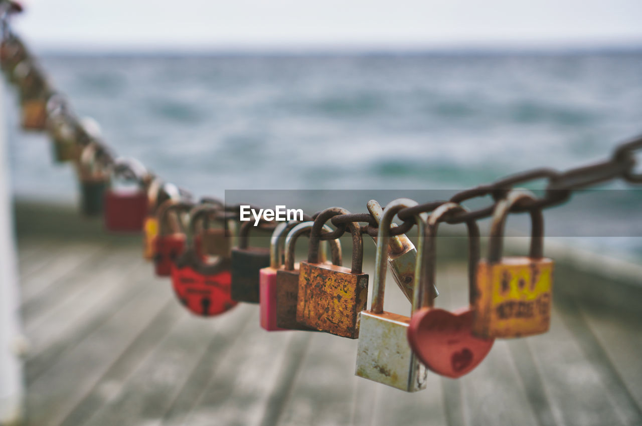 Close-up of padlocks hanging on railing against sea