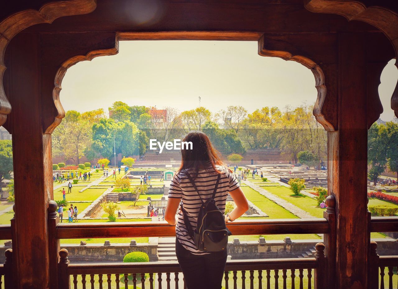 Rear view of woman standing by railing against sky