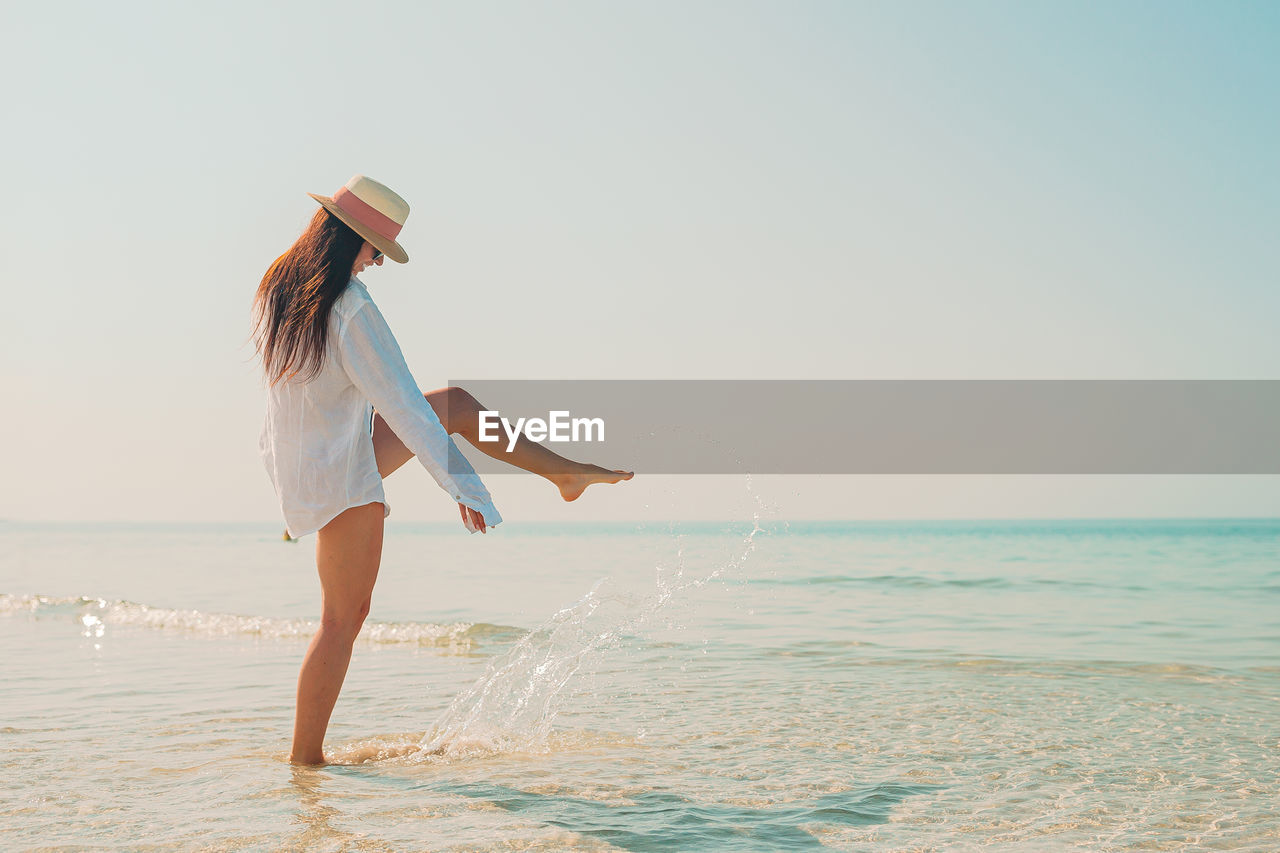 Woman splashing water on beach