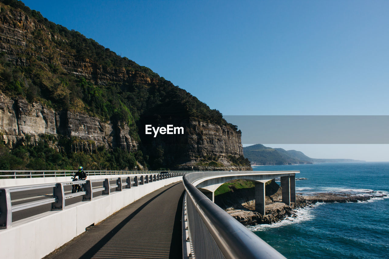 Bridge by sea against clear blue sky