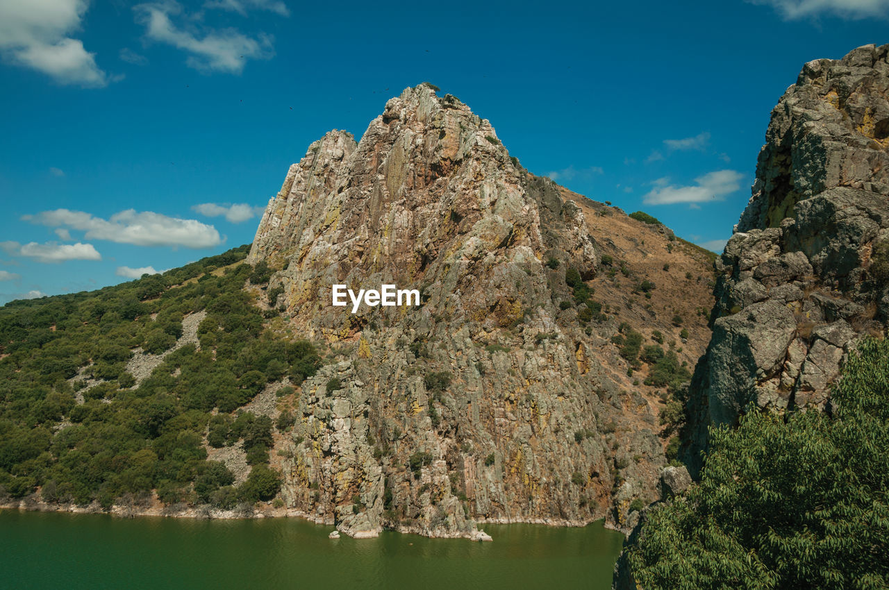 SCENIC VIEW OF ROCK FORMATION AMIDST TREES AGAINST SKY