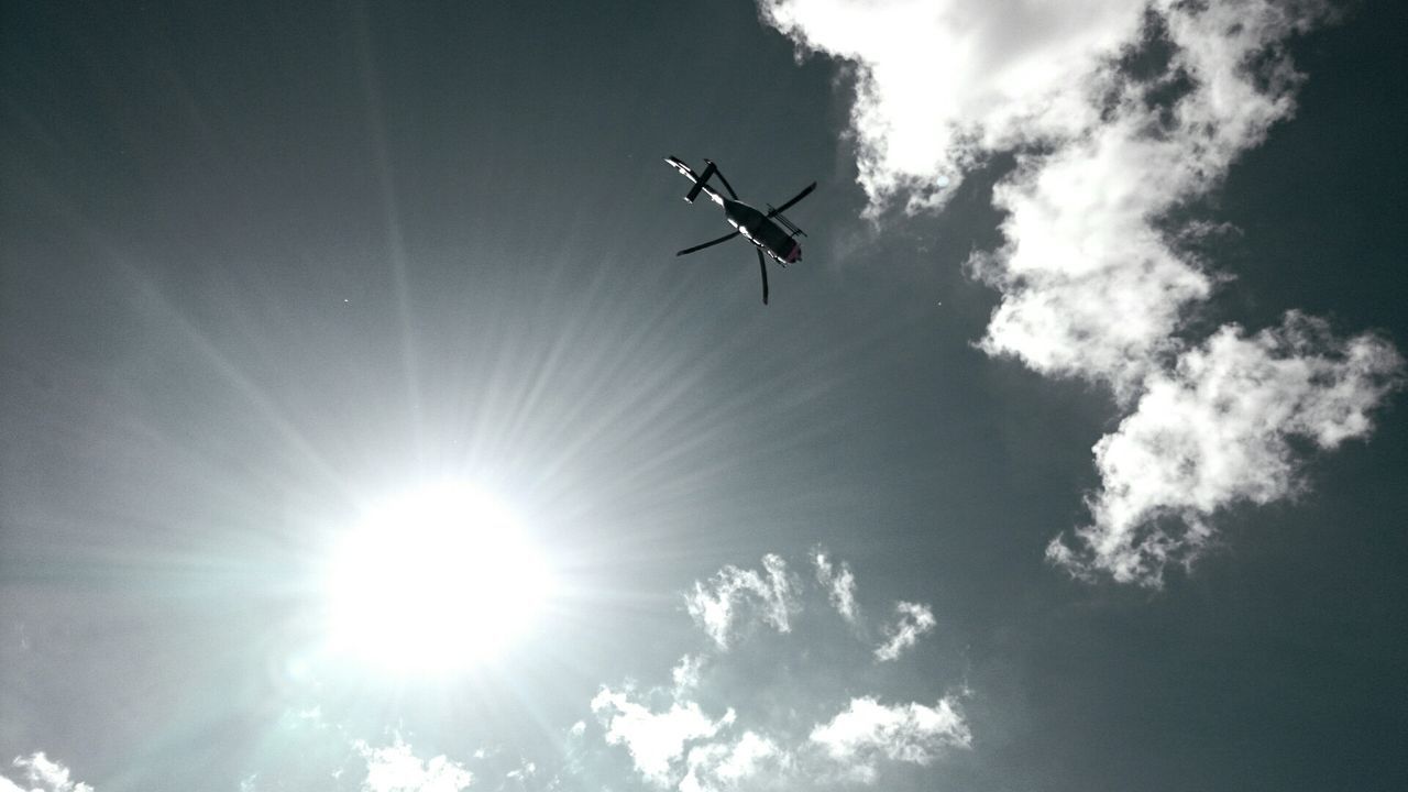 Low angle view of helicopter flying in sky on a sunny day