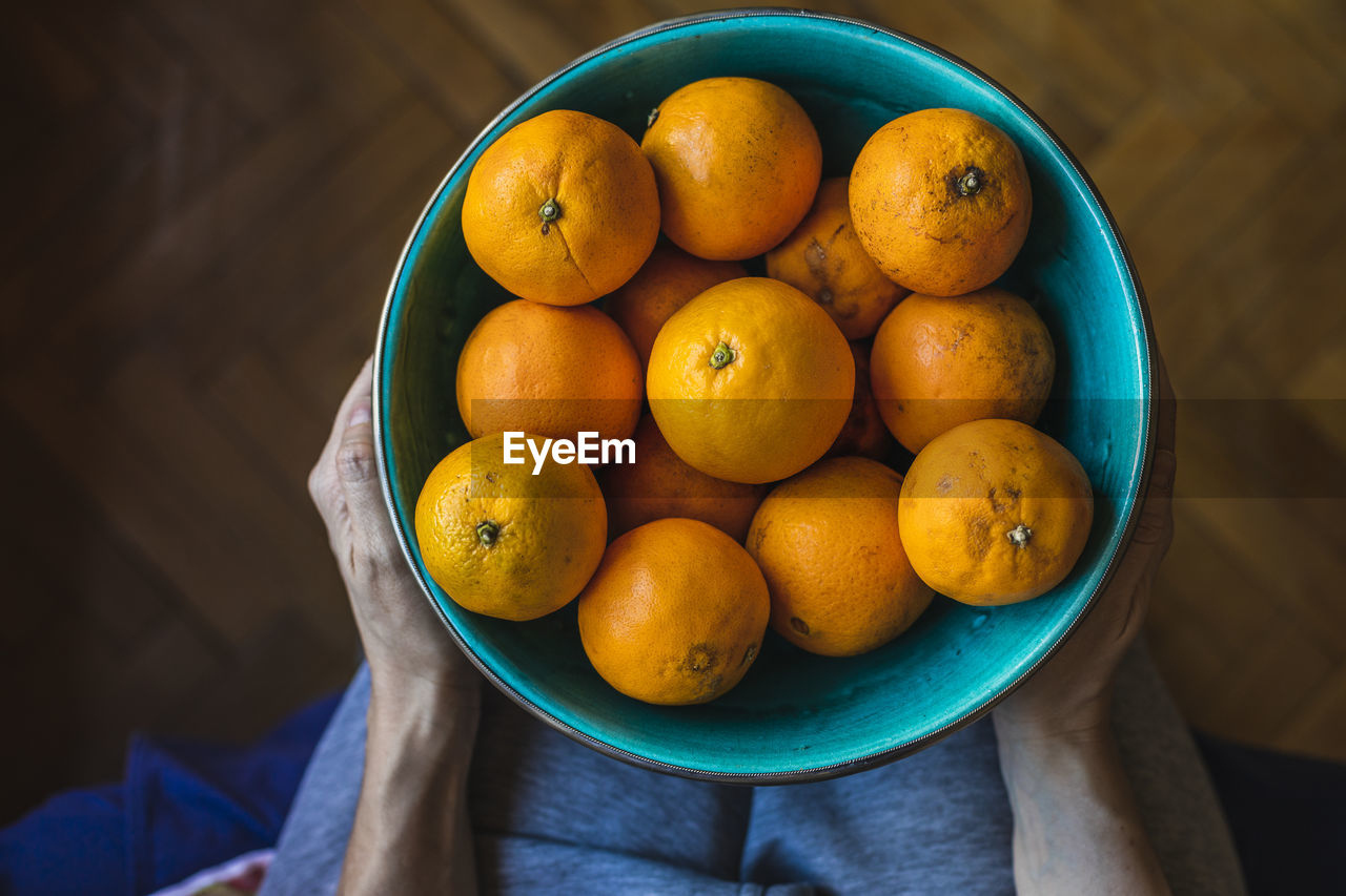 A mother and son place organic oranges in a green bowl.