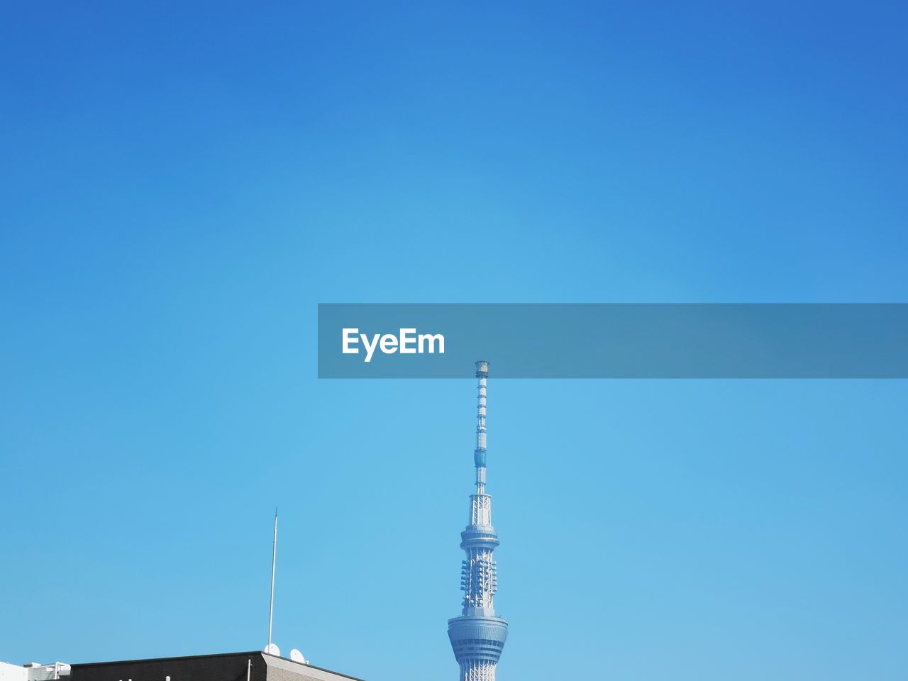 Low angle view of communications tower against clear blue sky