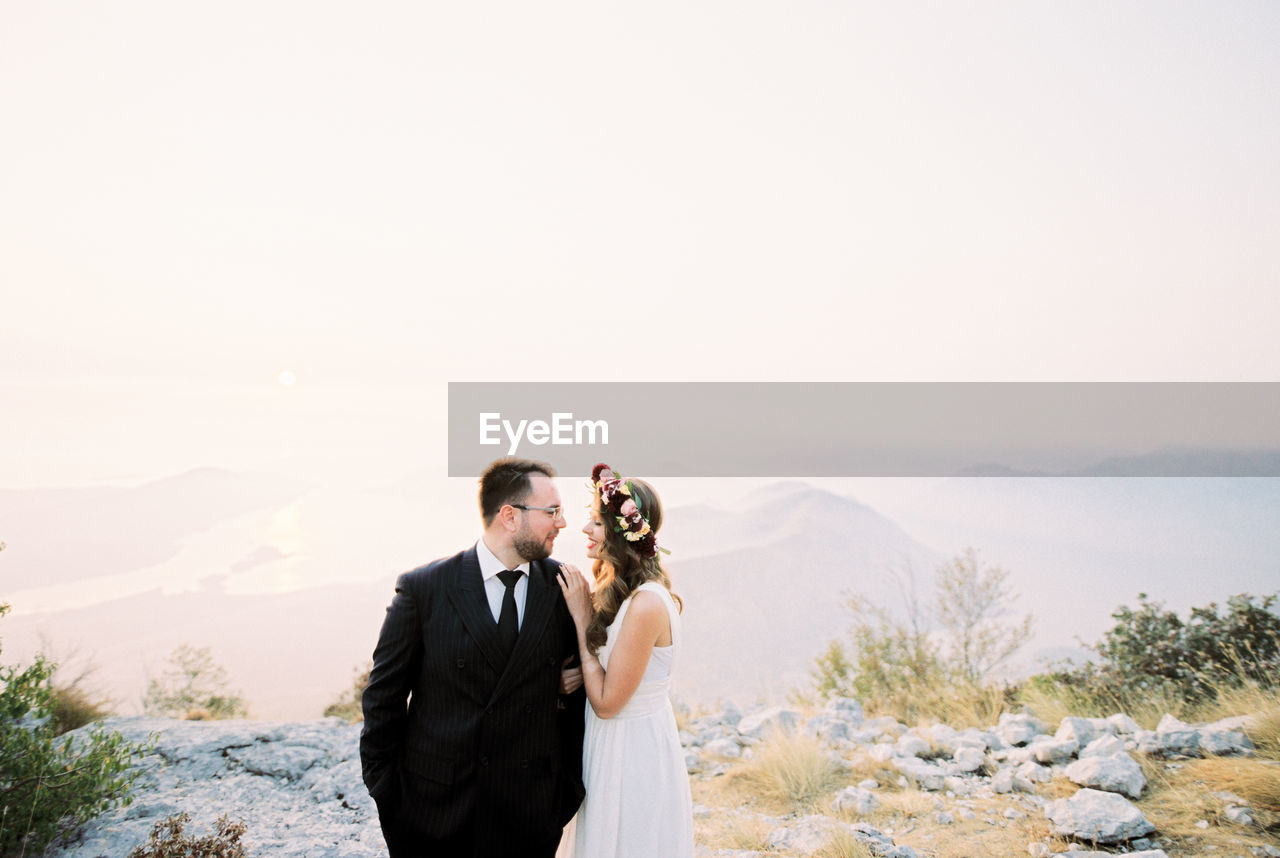 portrait of smiling couple standing against sea