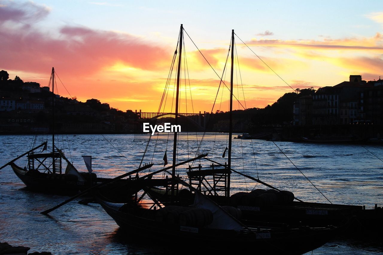 Silhouette boats in calm sea at dusk