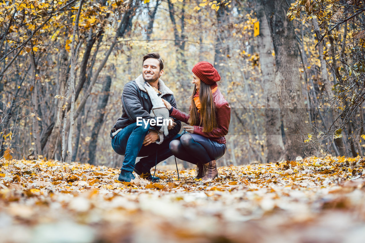 Couple crouching on field during autumn