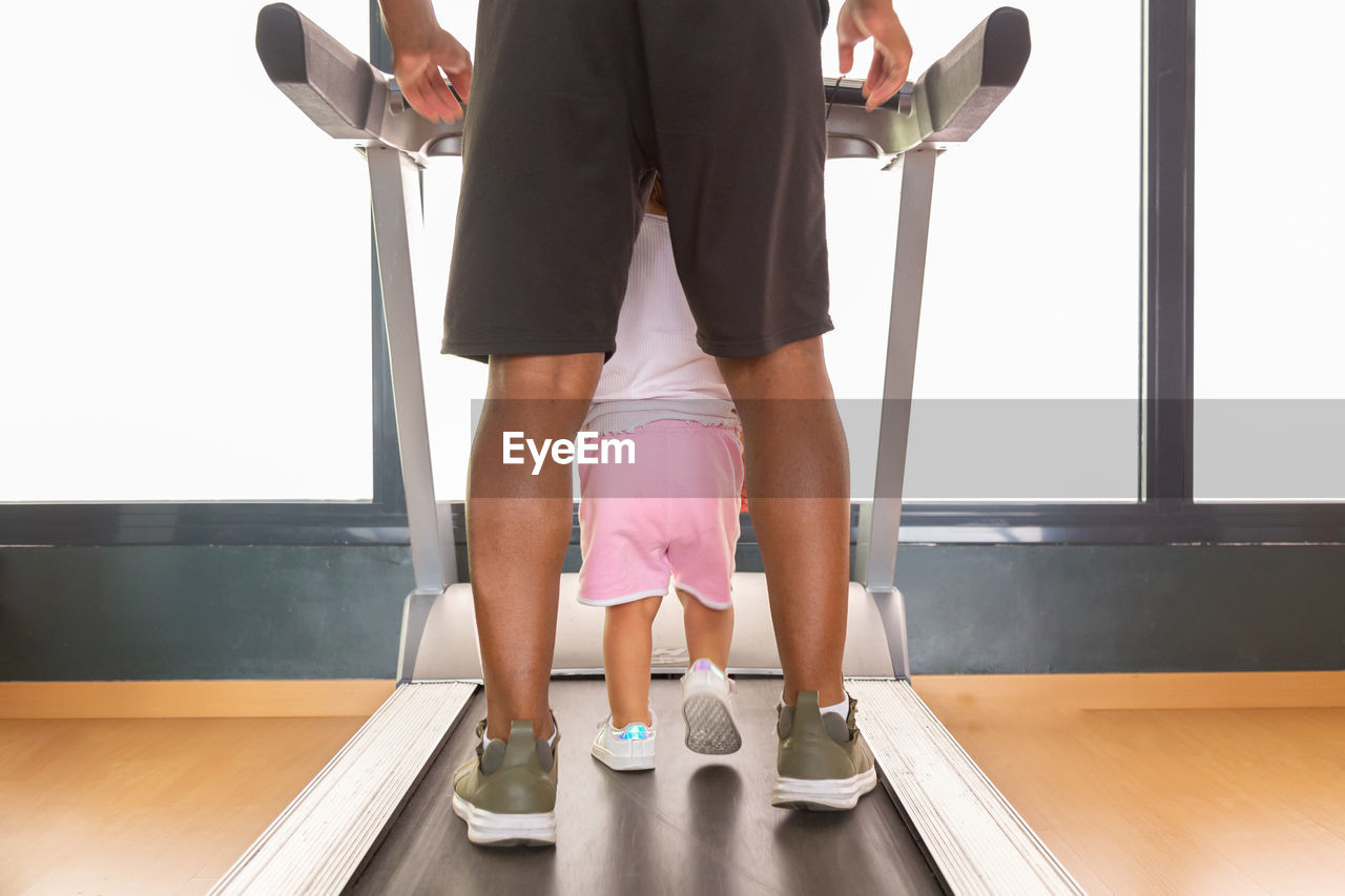 Crop dad and kid walking on treadmill