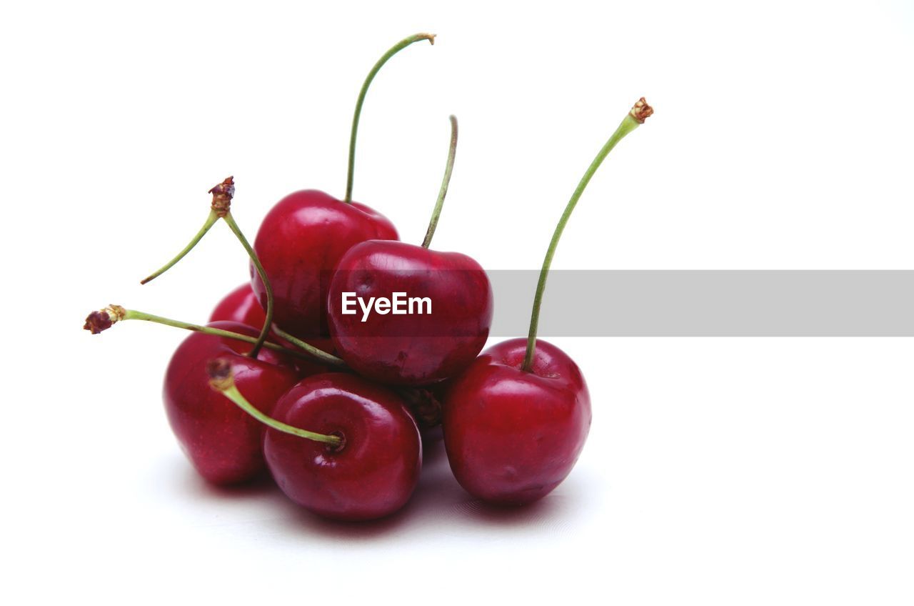 CLOSE-UP OF RED BERRIES OVER WHITE BACKGROUND