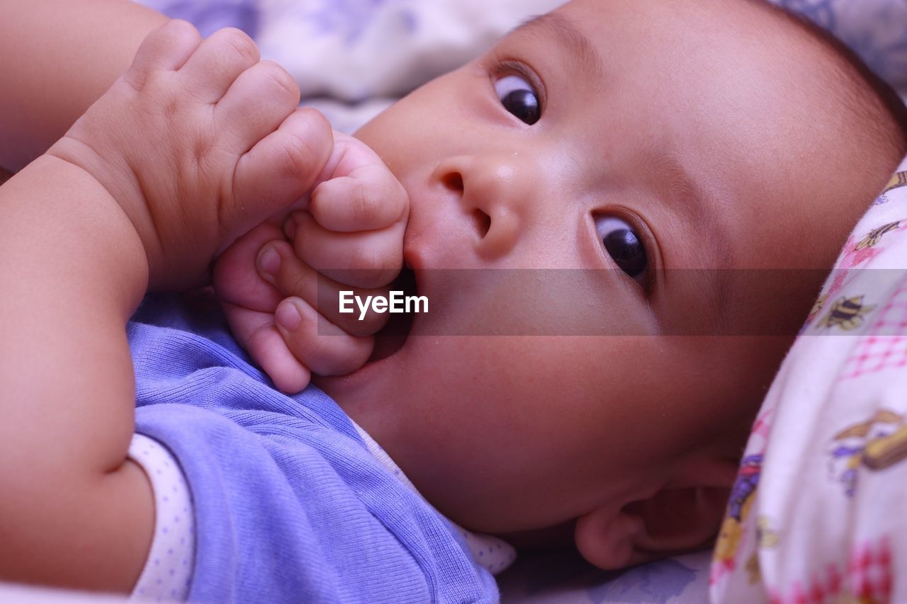 Close-up portrait of cute baby boy lying on bed at home