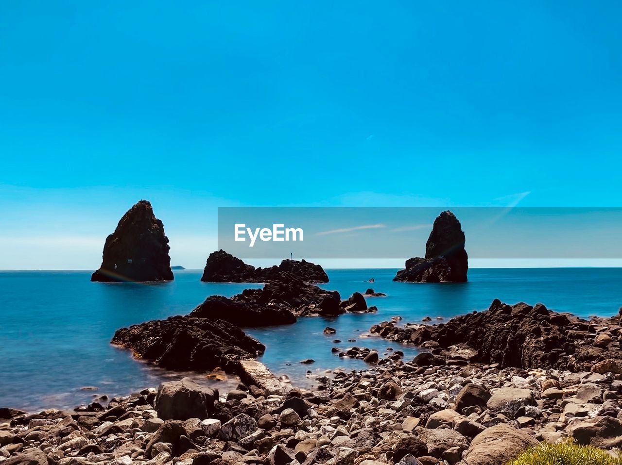 Scenic view of rocks in sea against blue sky