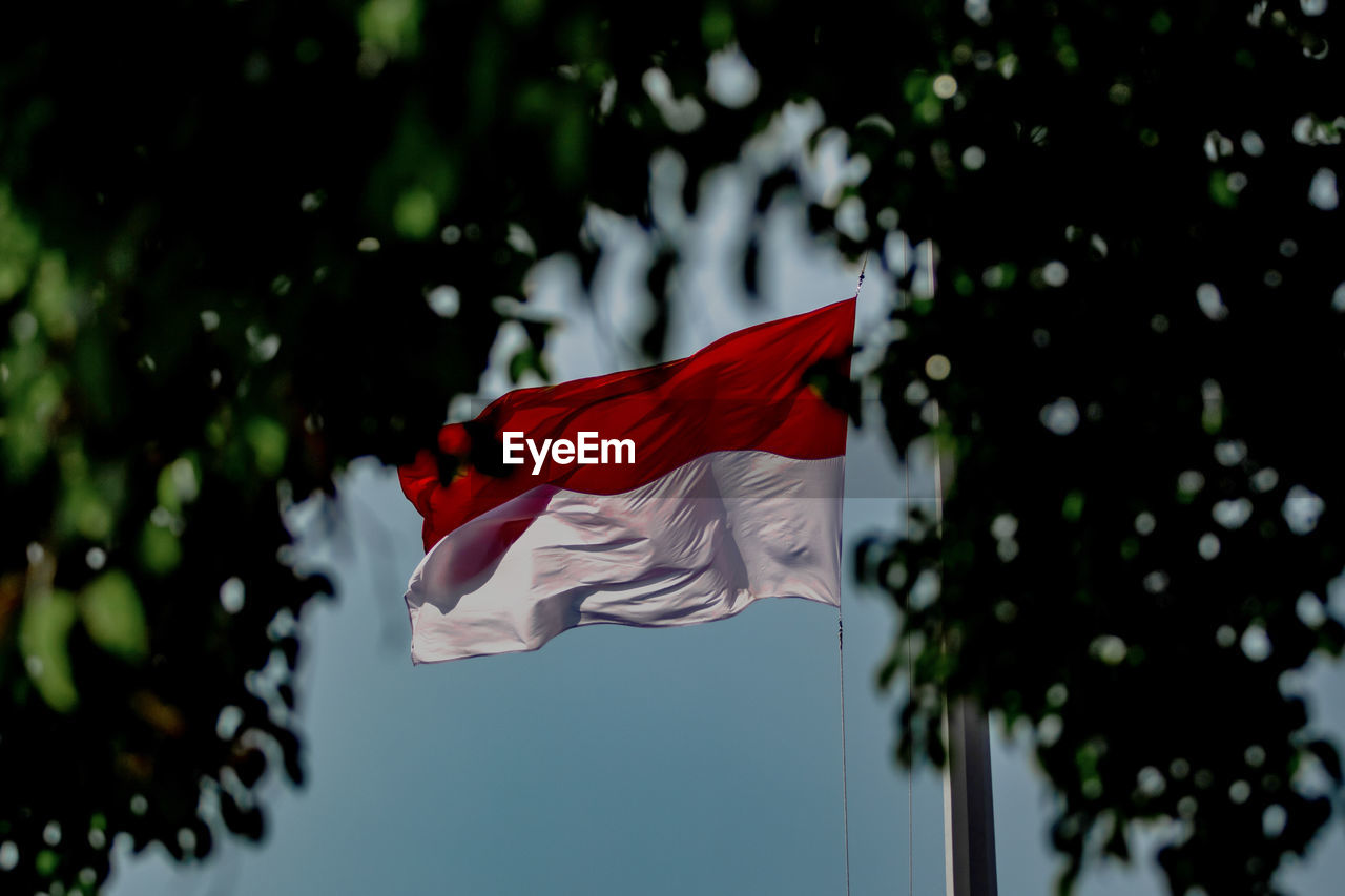 LOW ANGLE VIEW OF RED FLAG AGAINST THE SKY