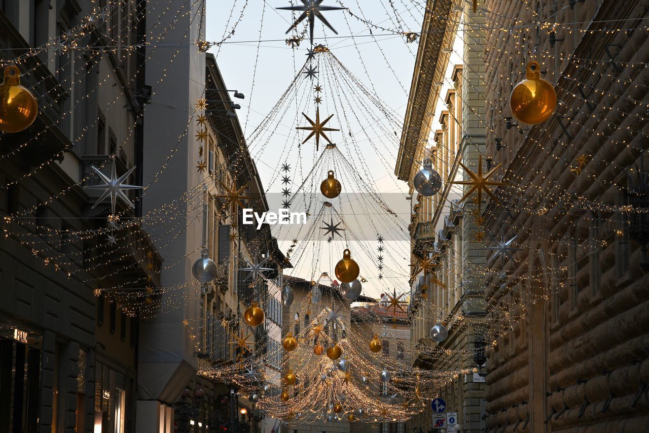 Low angle view of christmas decorations hanging amidst buildings