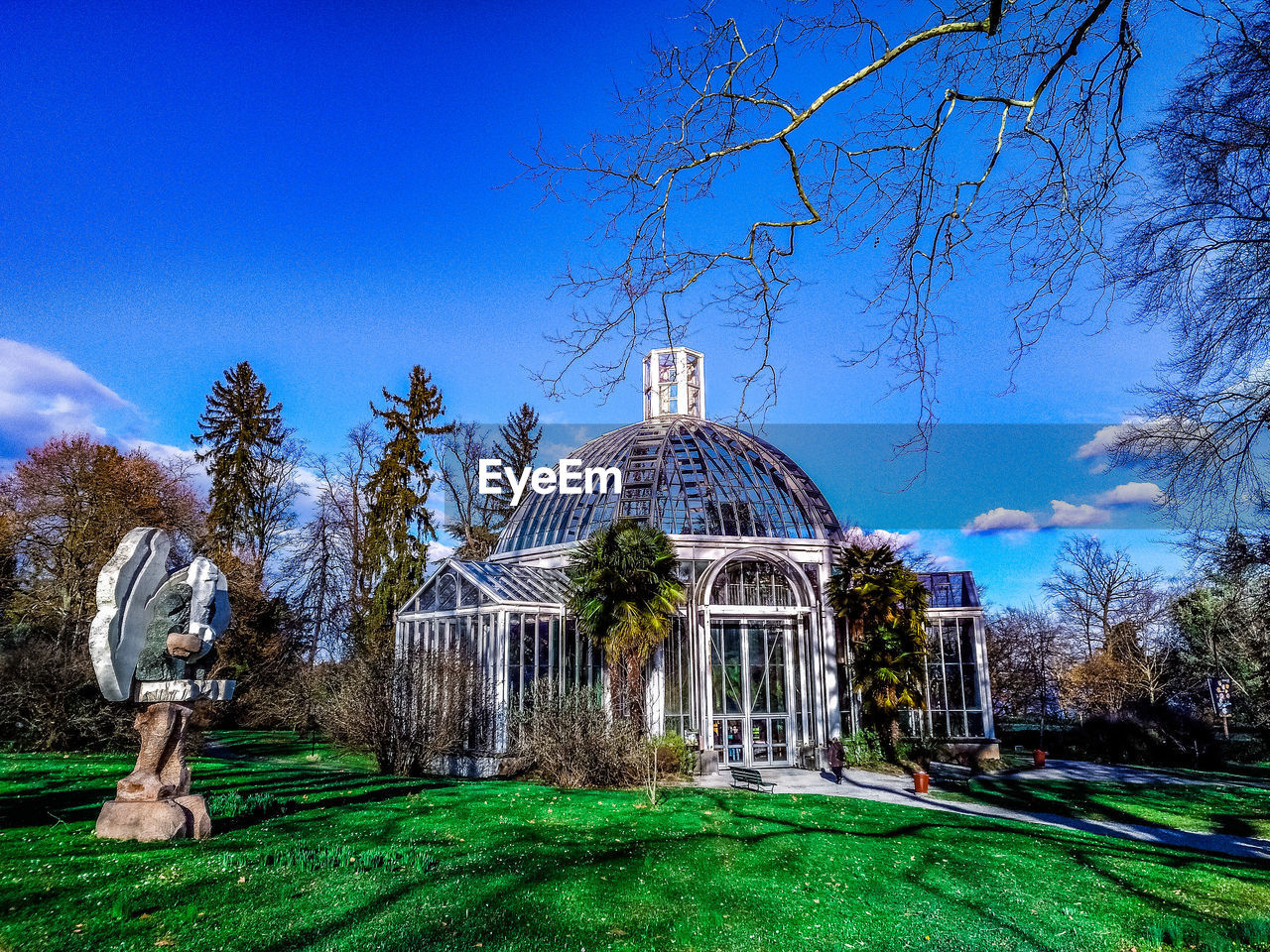 VIEW OF BUILT STRUCTURE WITH TREES AGAINST BLUE SKY