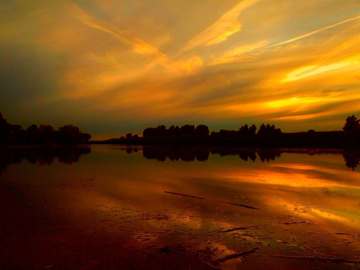 Scenic view of river by silhouette trees against sky