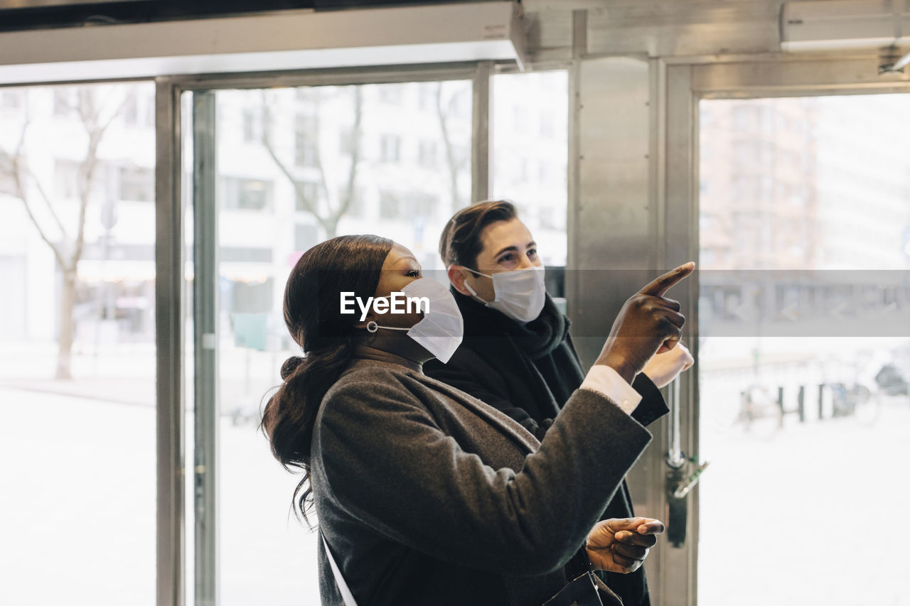 Male and female colleagues pointing while standing in store during pandemic