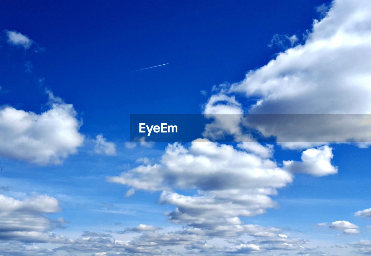 LOW ANGLE VIEW OF VAPOR TRAILS IN BLUE SKY