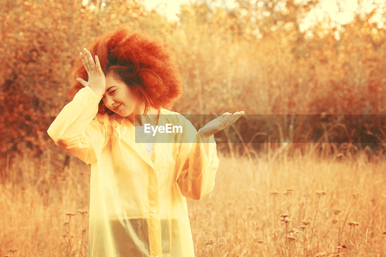 YOUNG WOMAN STANDING IN FIELD