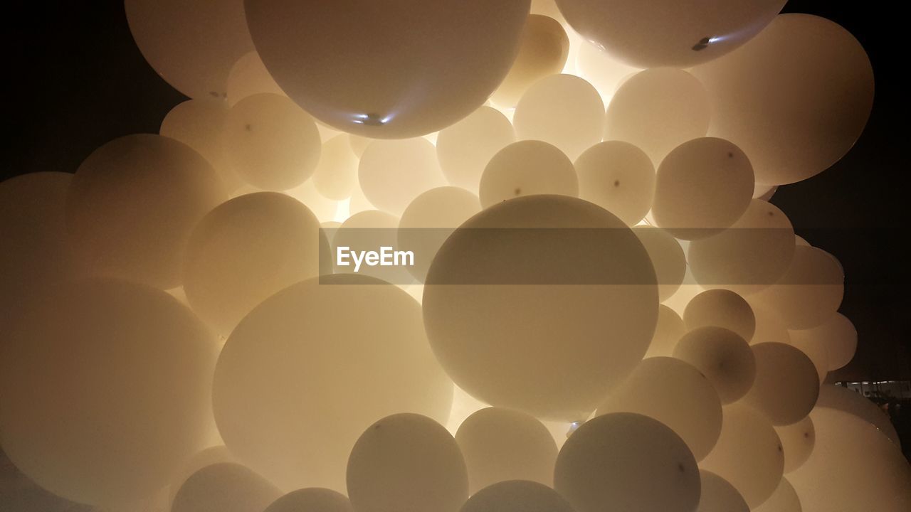 LOW ANGLE VIEW OF BALLOONS AGAINST ILLUMINATED CEILING