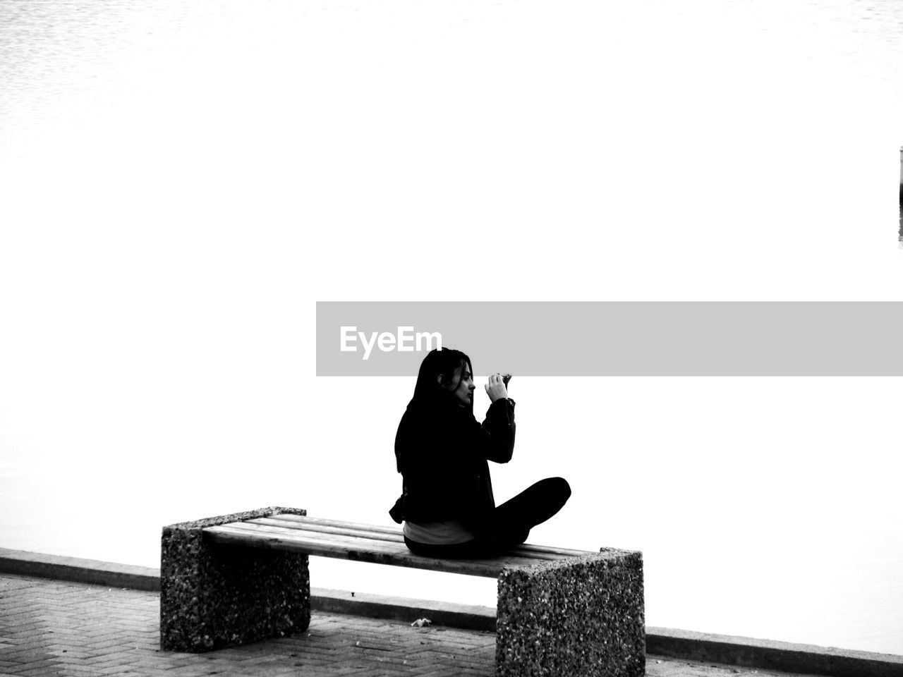 REAR VIEW OF WOMAN SITTING ON BENCH