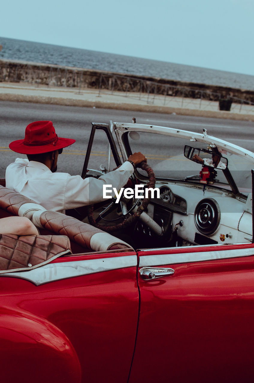 Man driving vintage car against sea