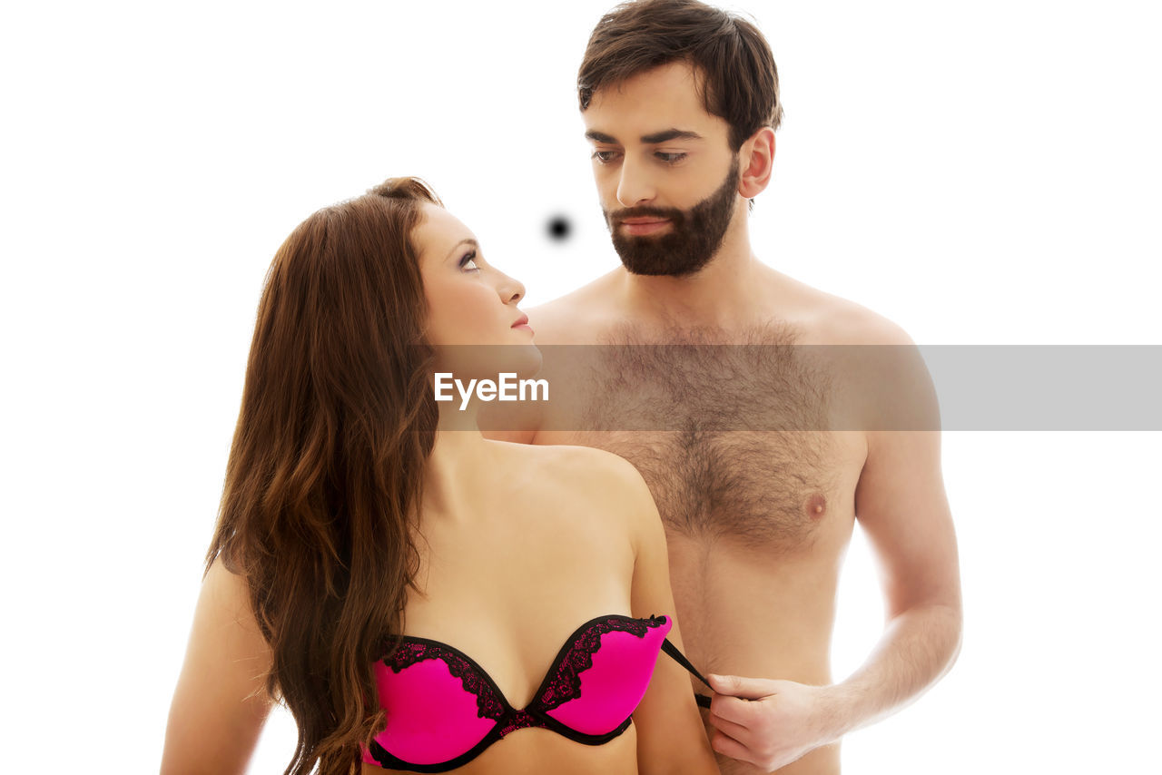 Man removing woman bra against white background