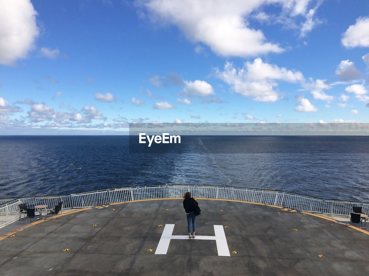 Woman standing at helipad in ship on sea against sky