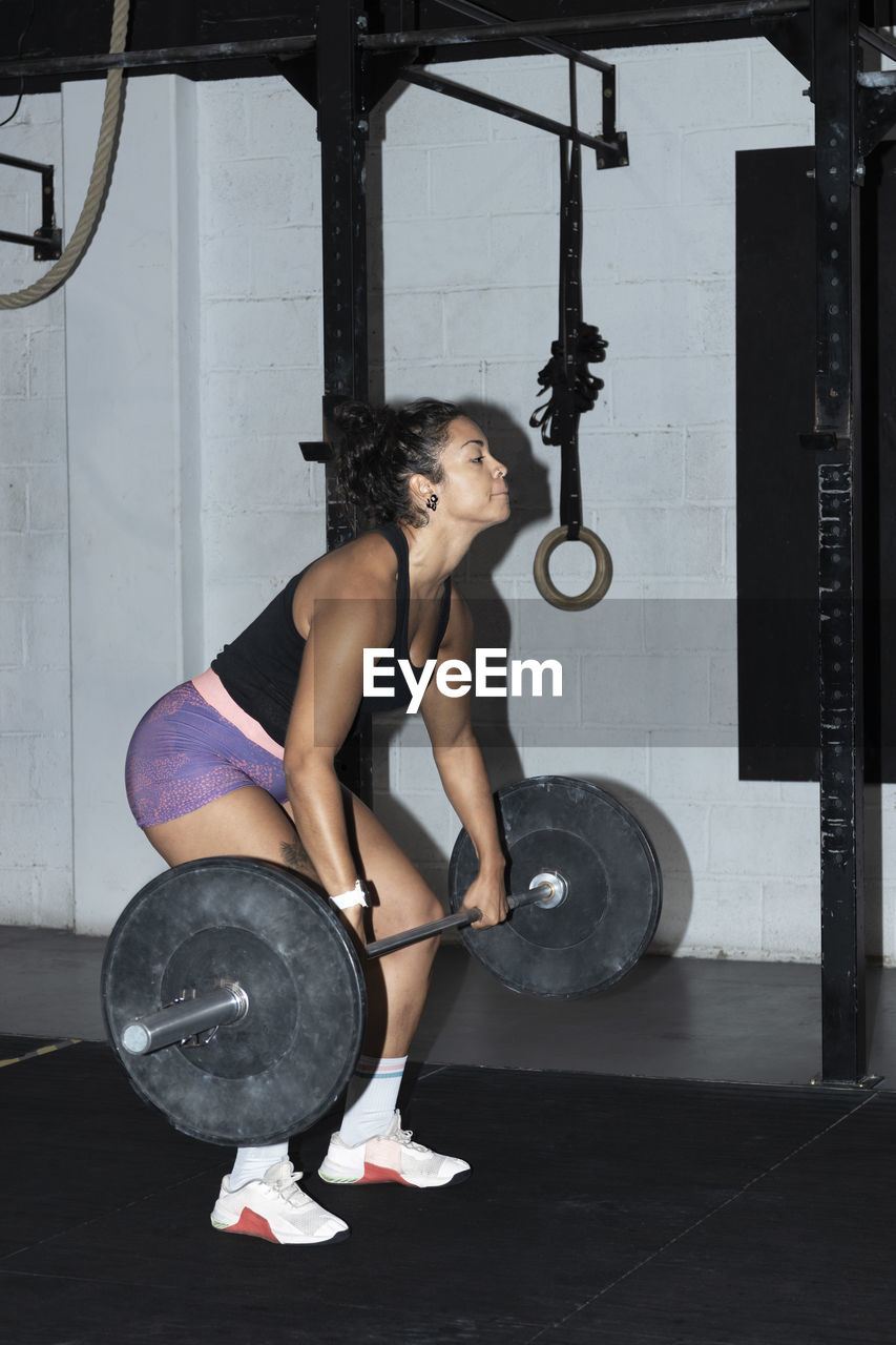 Young latin woman doing weightlifting at crossfit gym