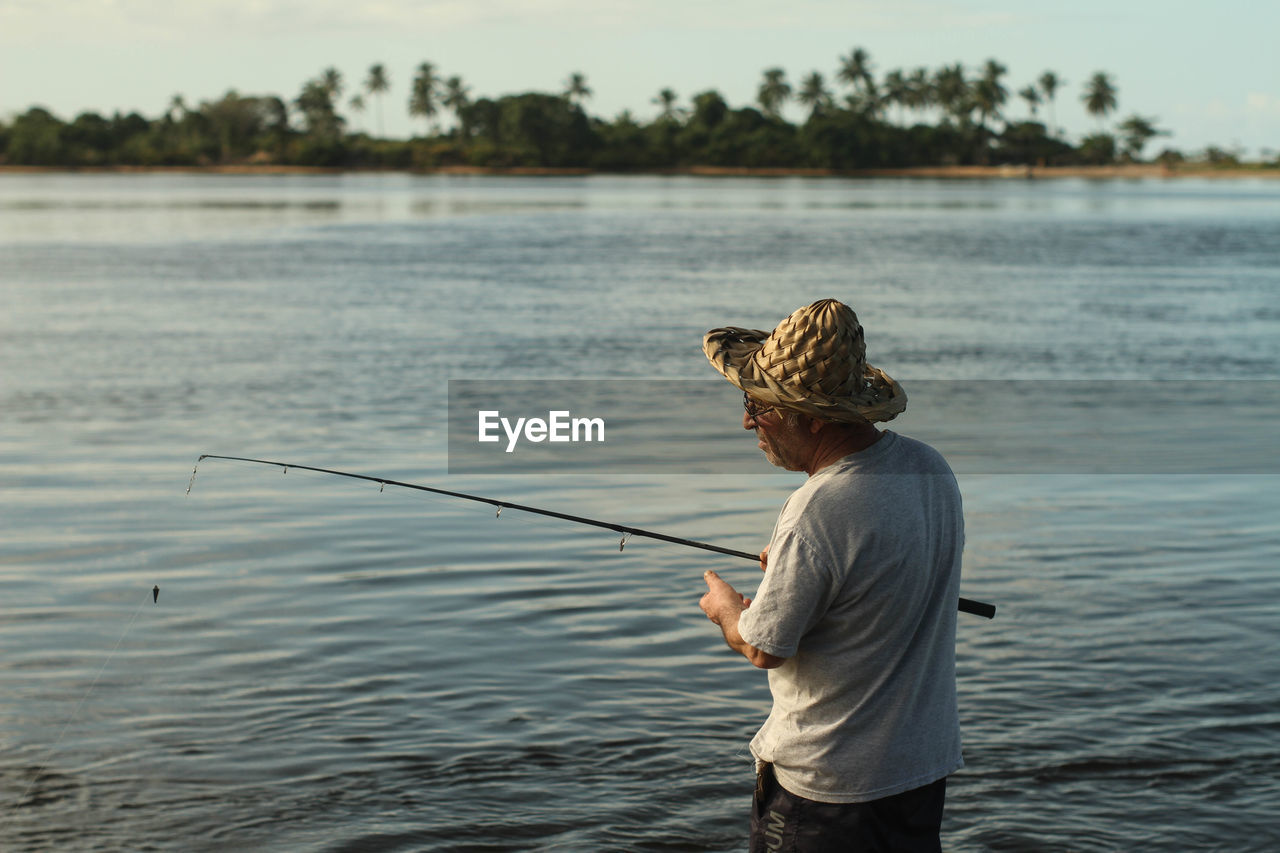 Senior man fishing in lake during sunset