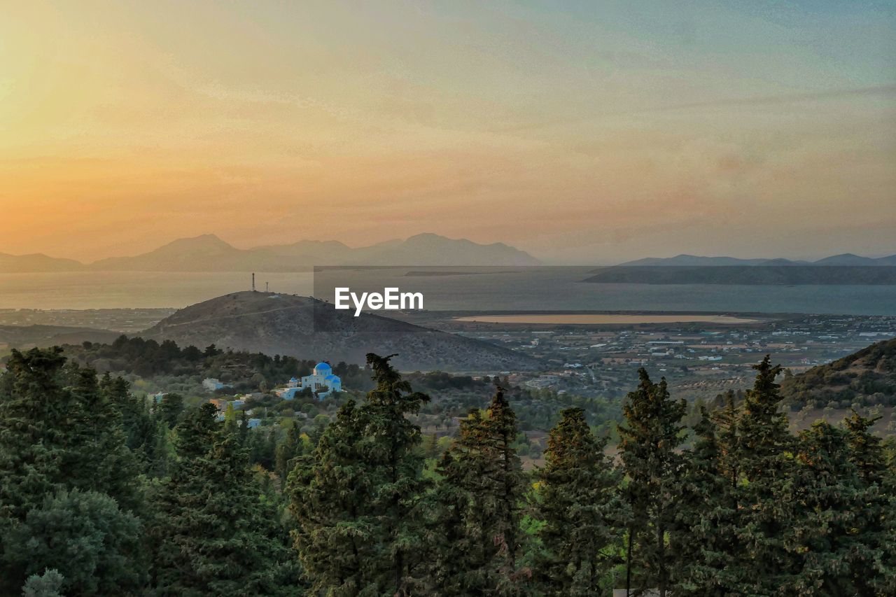 High angle sunset view of orthadow greek church set within hills and,trees by the sea 