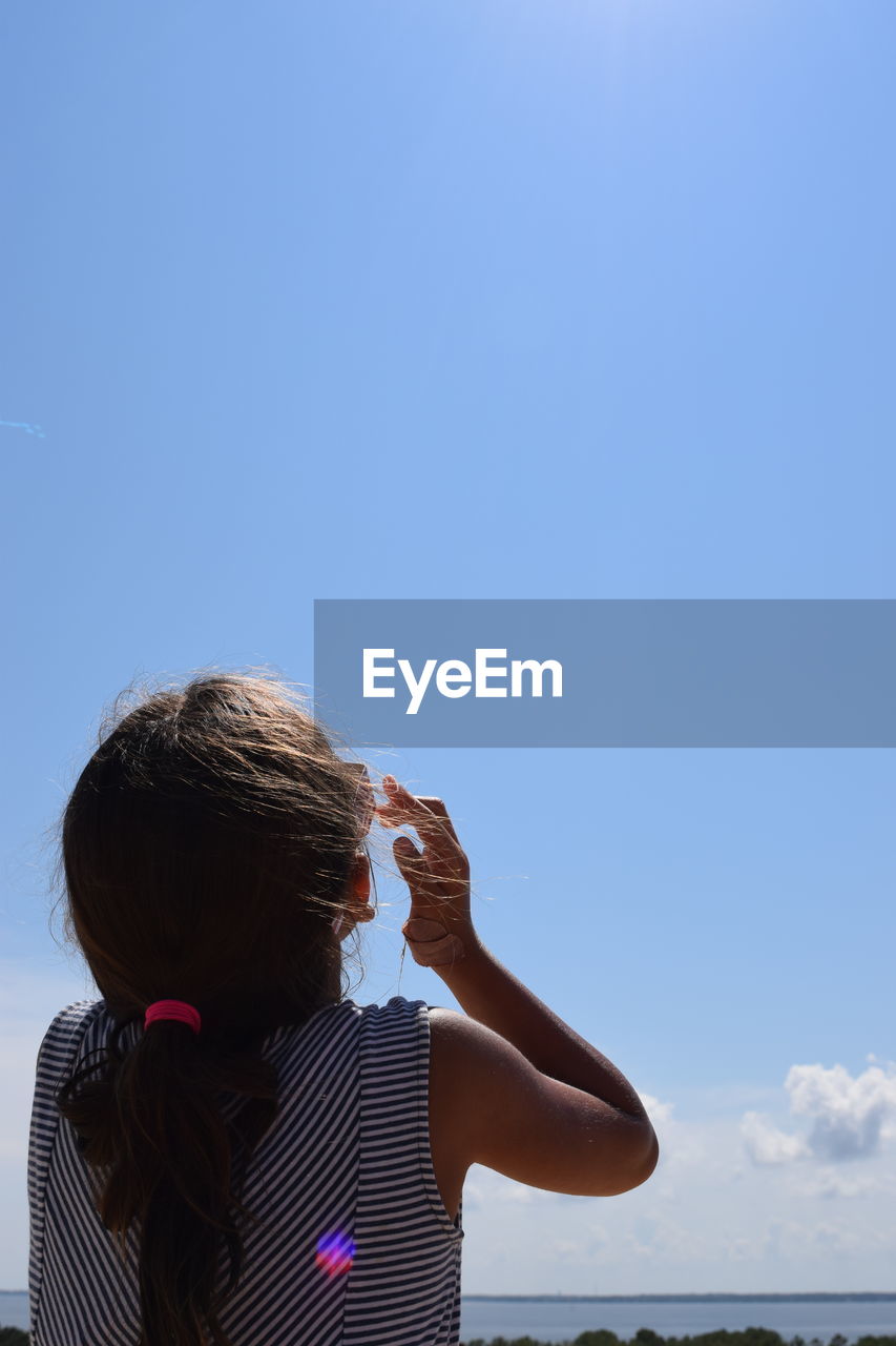 REAR VIEW OF WOMAN AGAINST CLEAR BLUE SKY