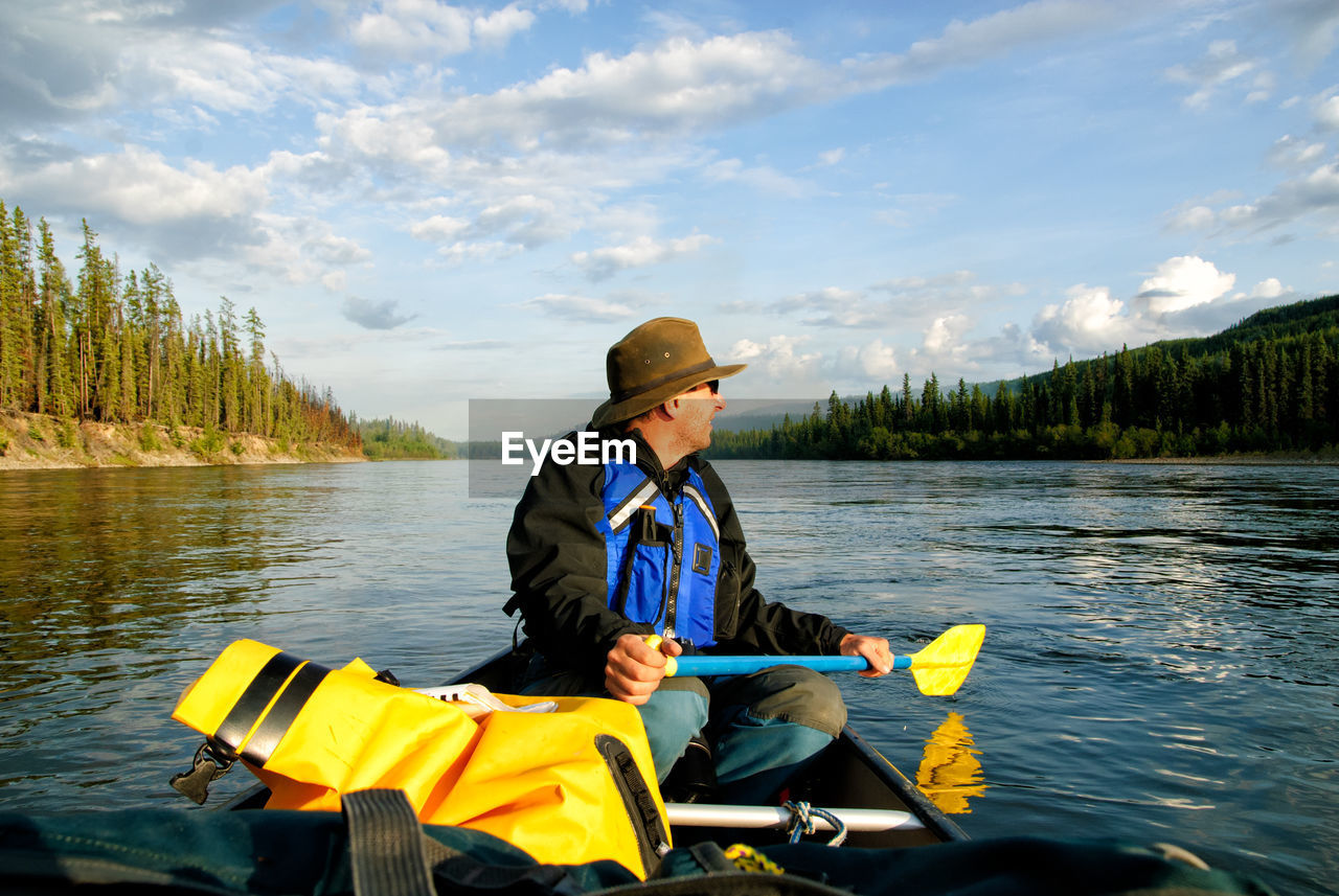 Man in canoe on yukon river against sky