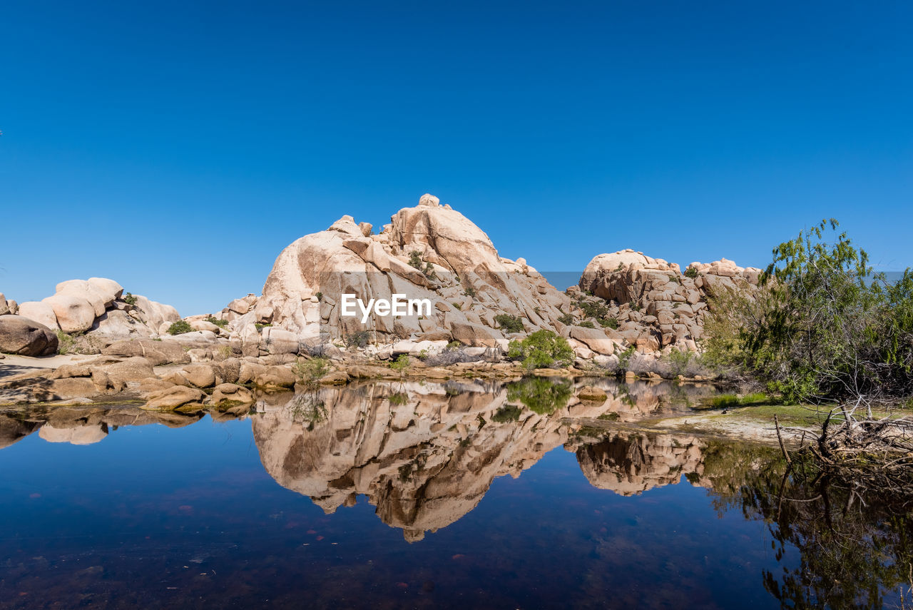 Scenic view of lake and mountains against clear blue sky