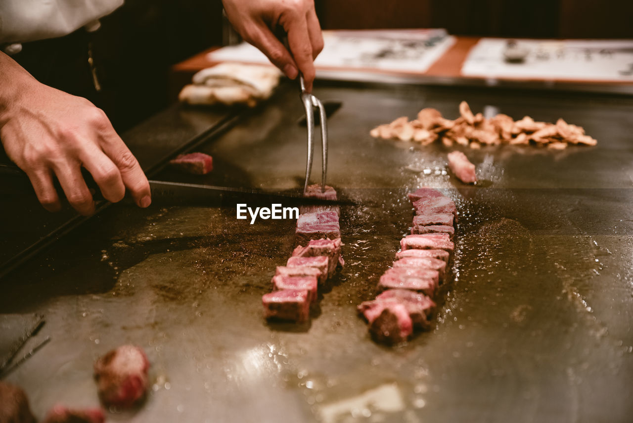 Midsection of man preparing meat in kitchen