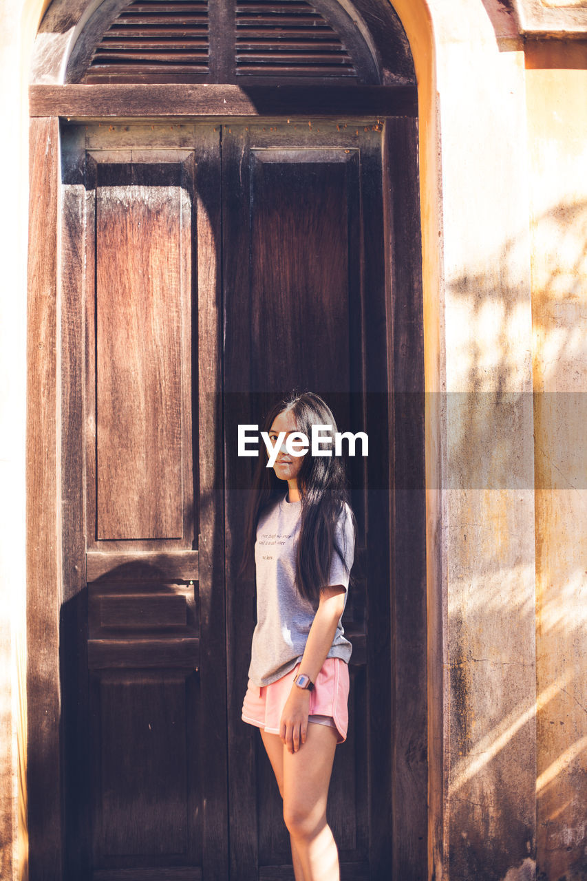 Portrait of woman standing against door