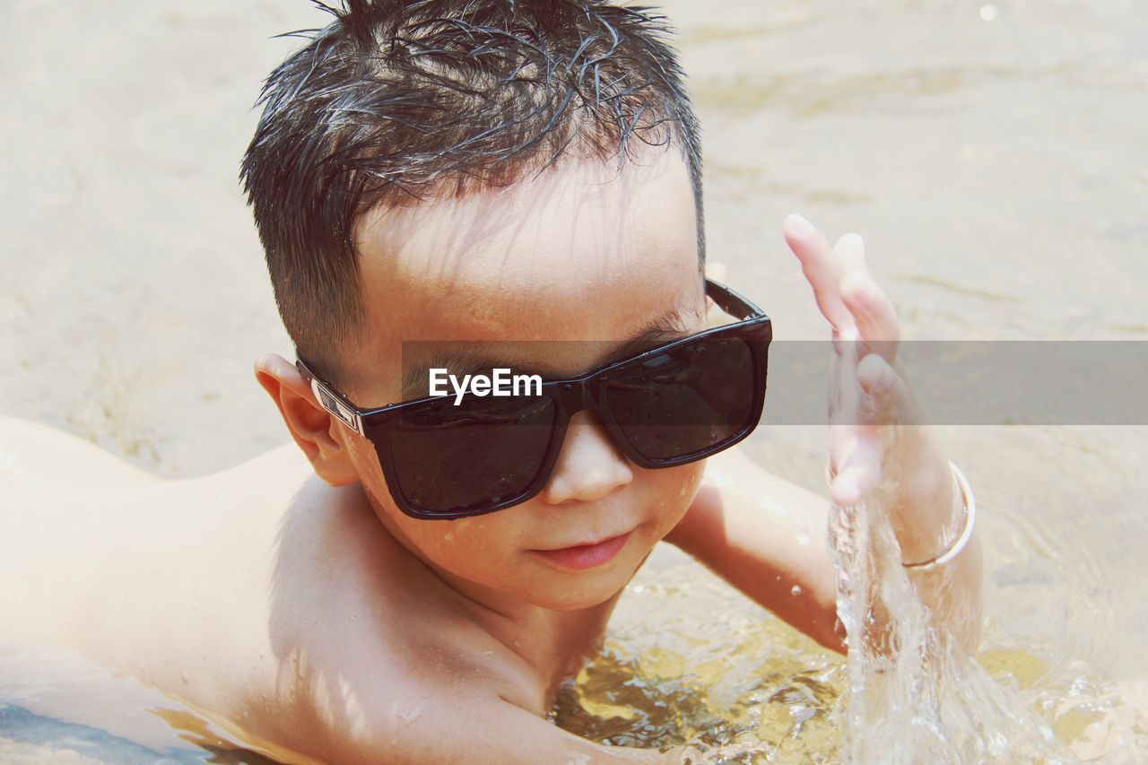 Portrait of shirtless boy with sunglasses at beach