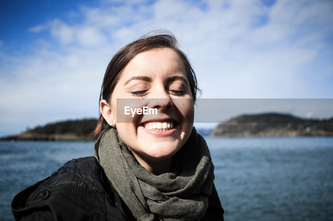 Portrait of smiling young woman against sea