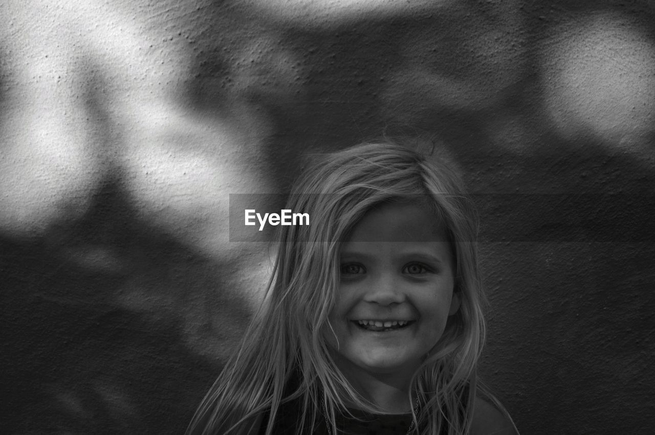 Portrait of smiling girl against wall