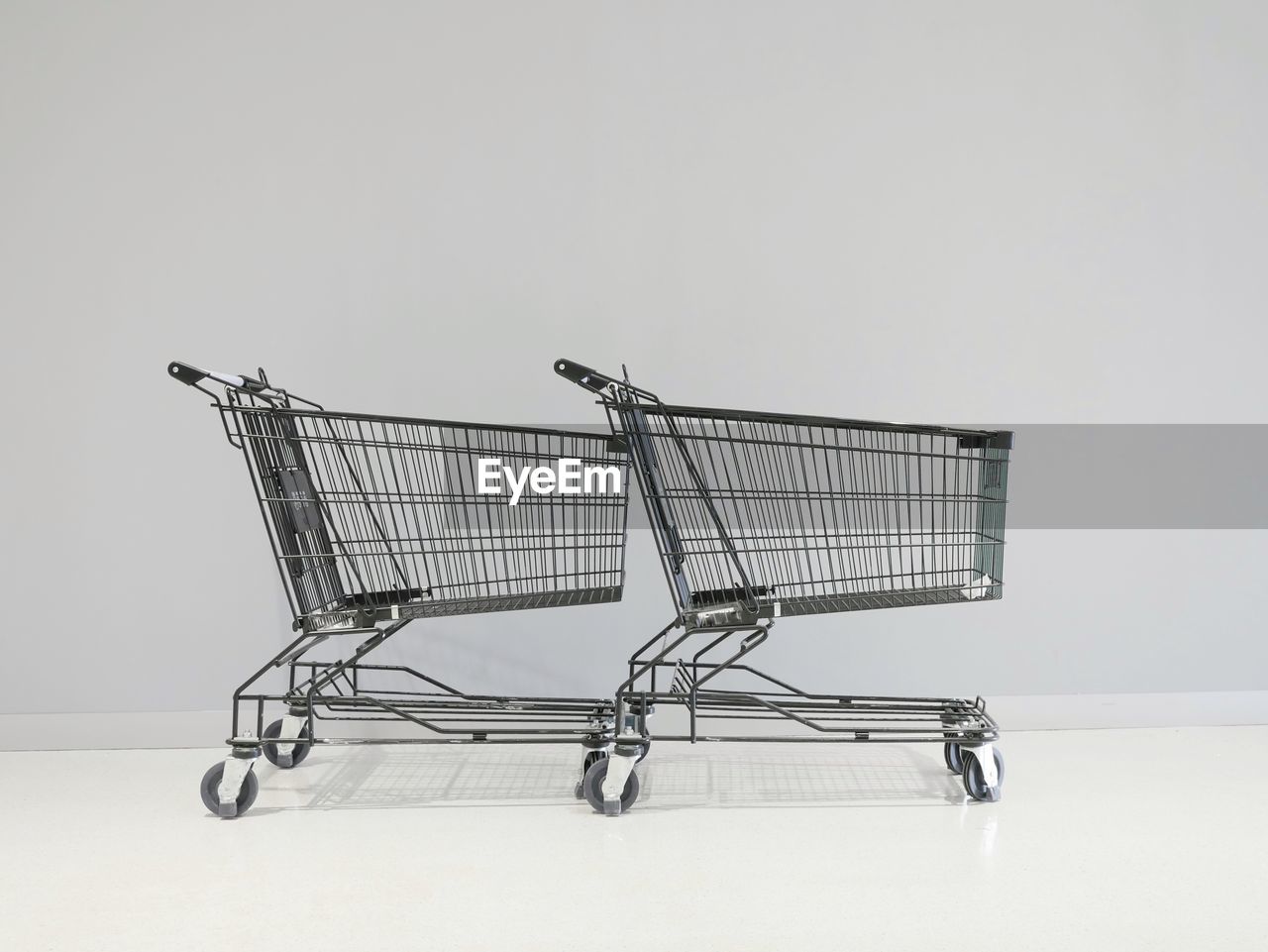Close-up of shopping carts against gray wall