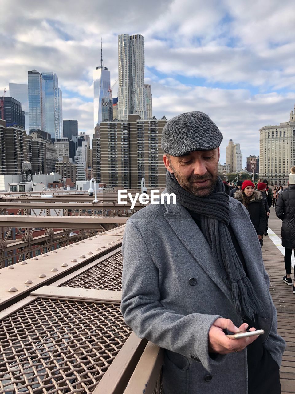 Man using phone while standing against buildings in city