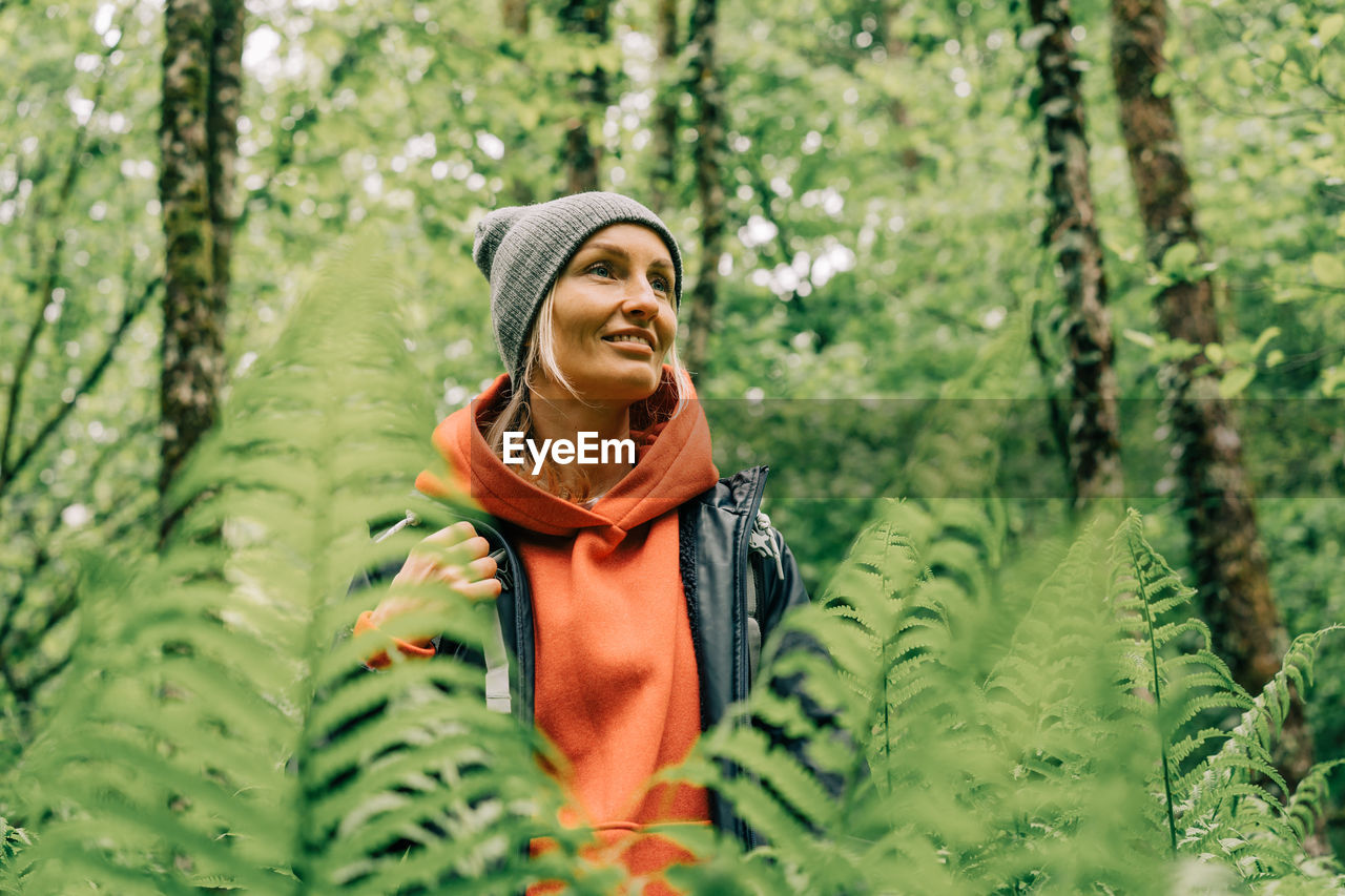 Portrait of a young wellness woman hiker in a thicket of ferns in a spring forest