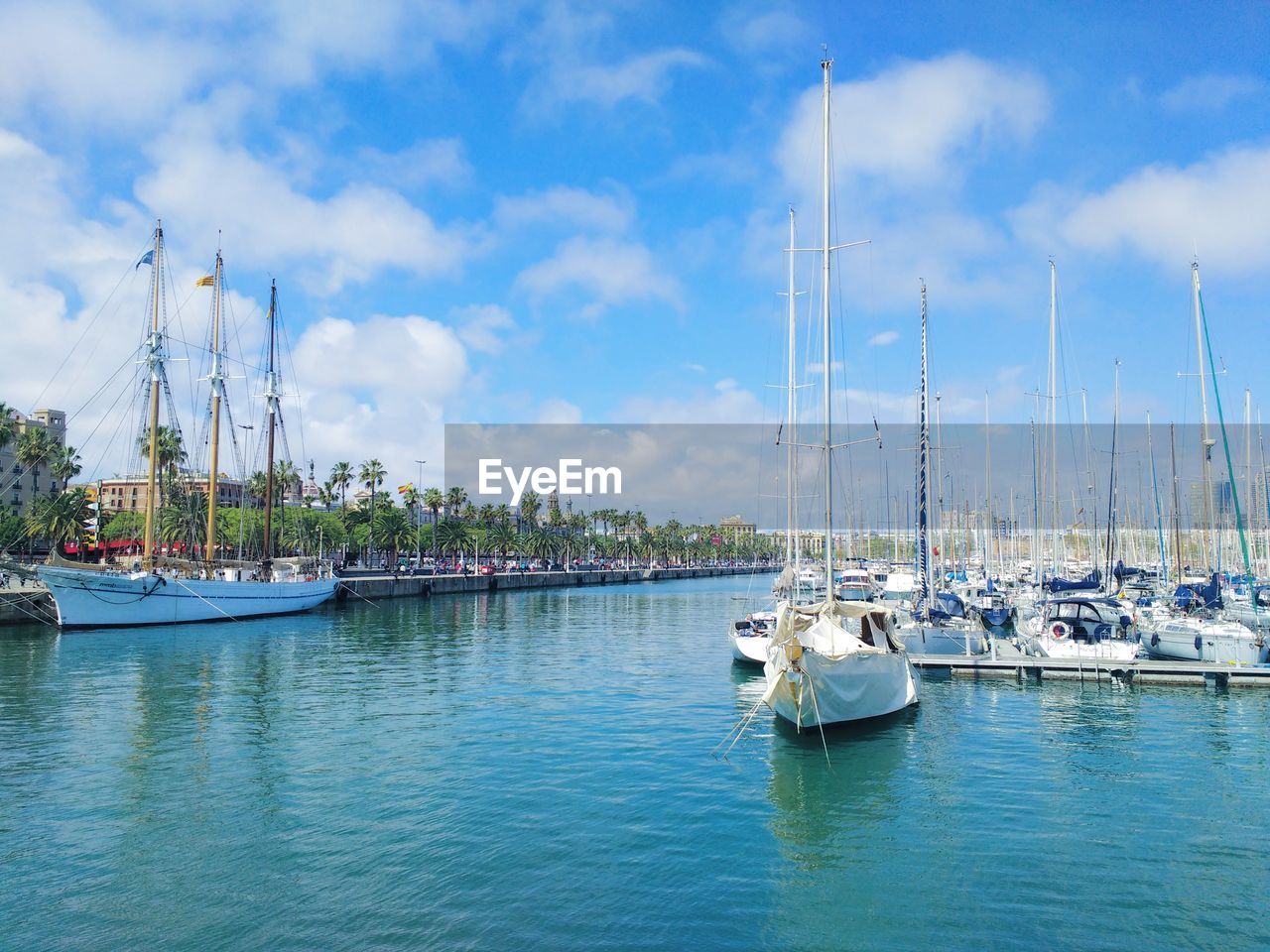 SAILBOATS MOORED IN HARBOR AGAINST SKY