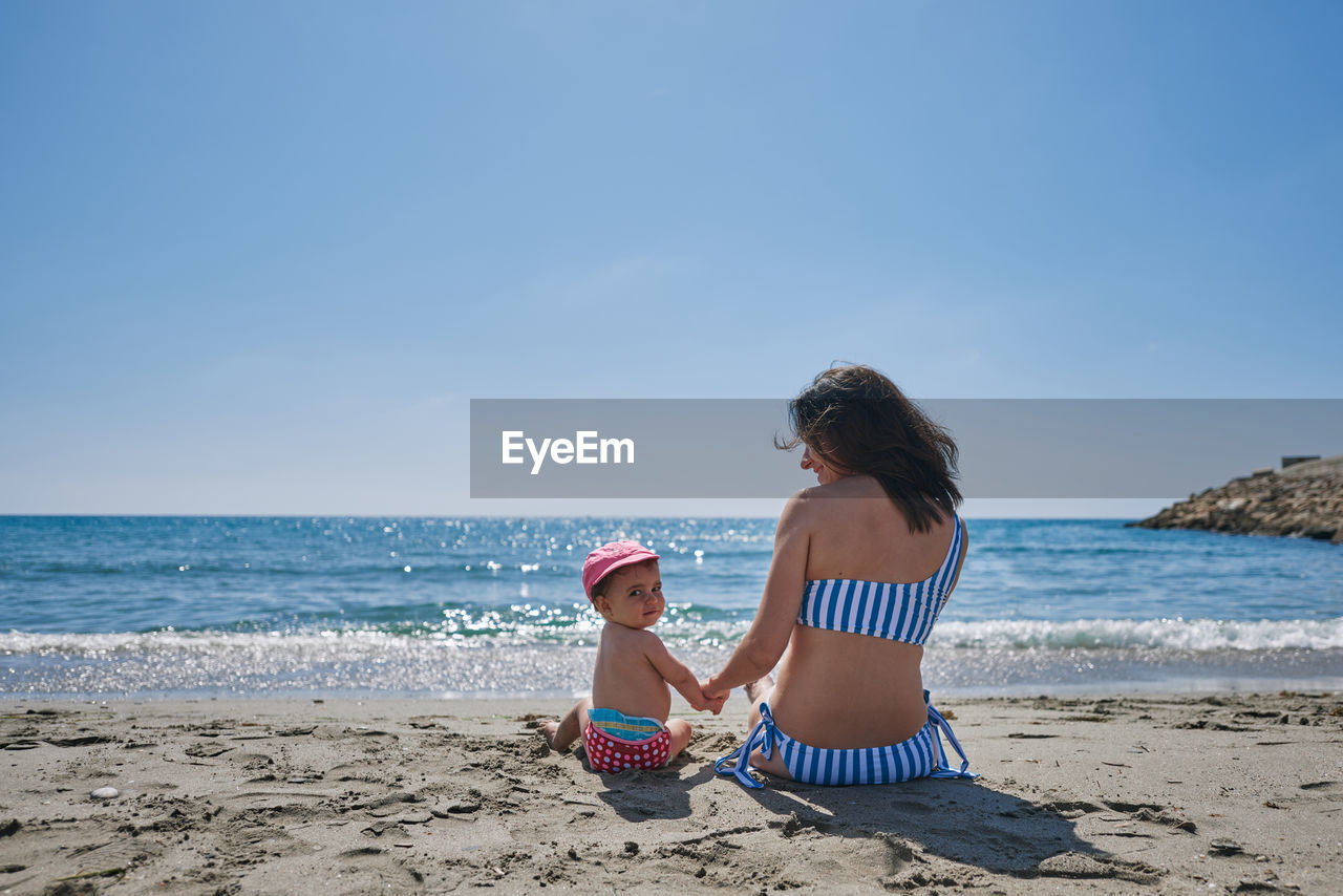 A young mother playing with her baby on the seashore. concept of reconciliation, play, love, holiday