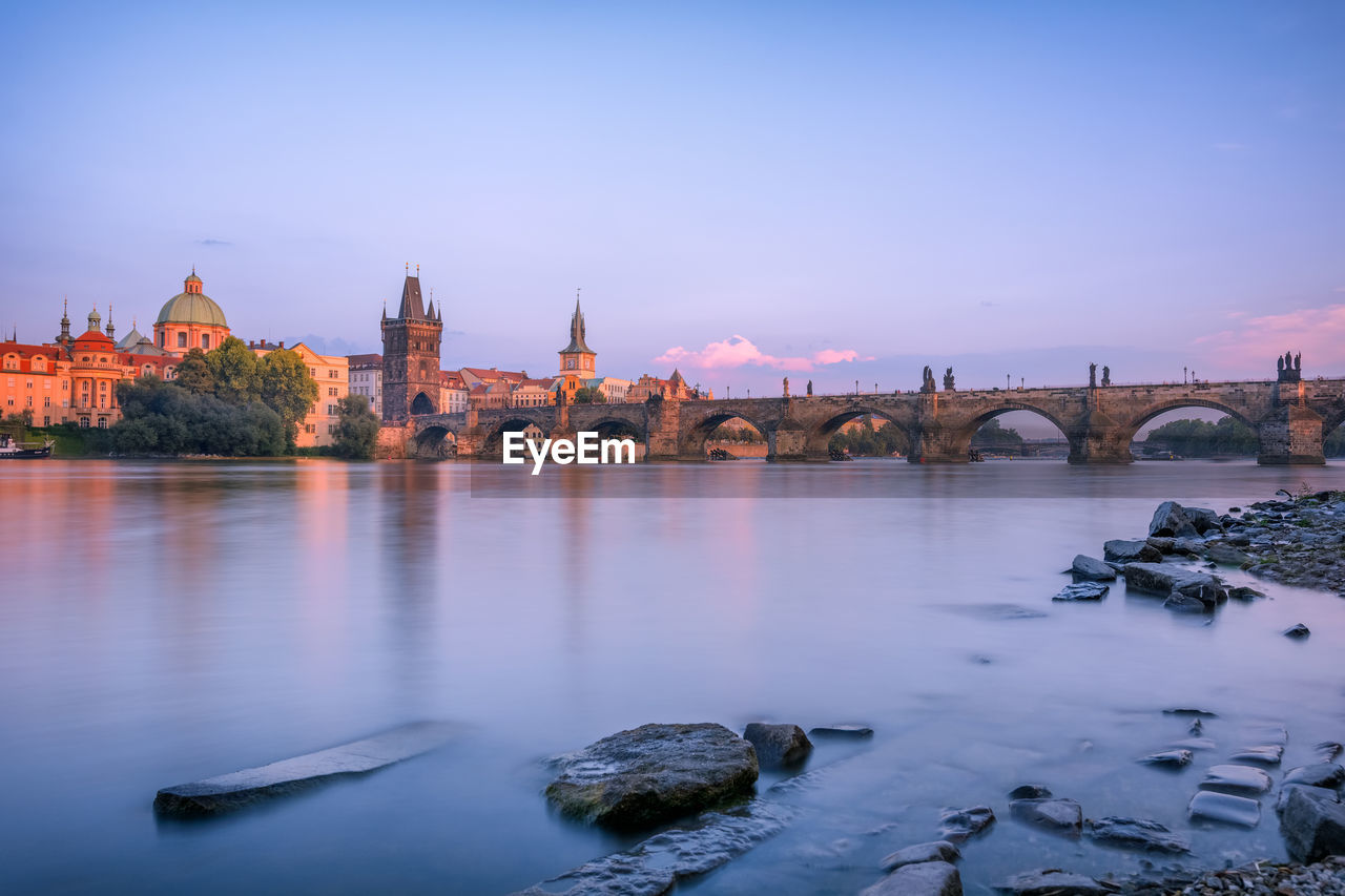 Charles bridge over river against sky during sunset