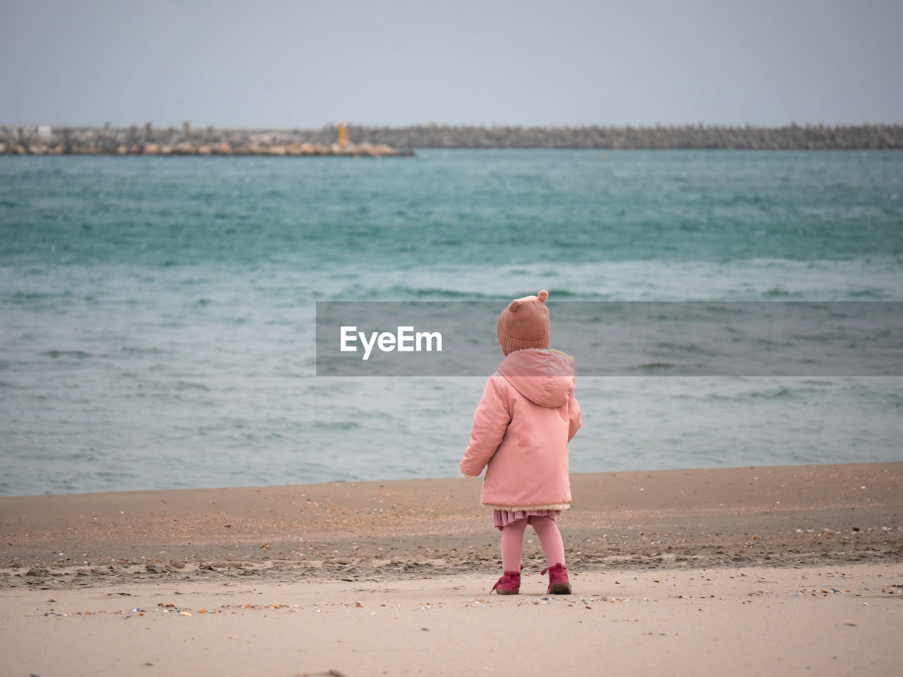 Little girl on the beach looking at the sea