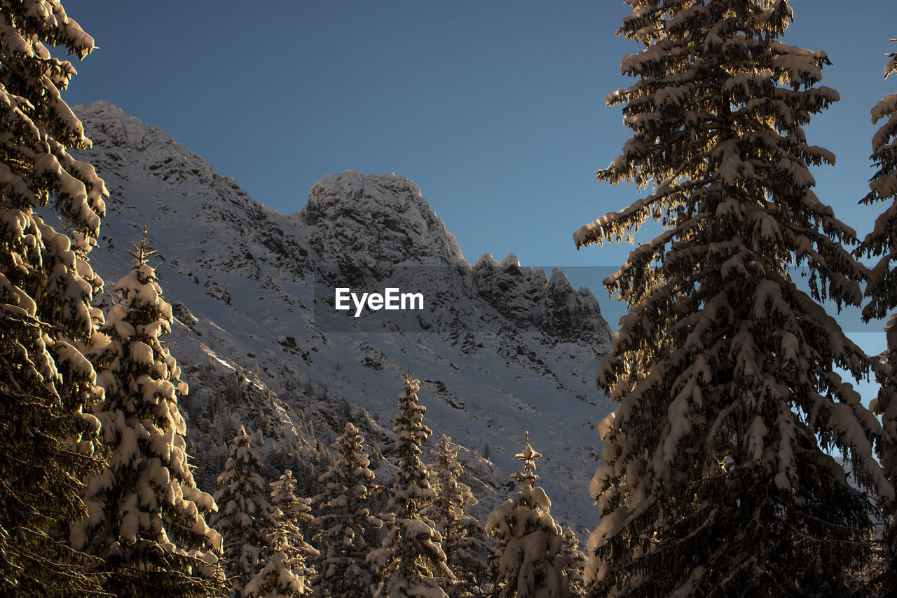 Low angle view of snowcapped mountains against clear sky